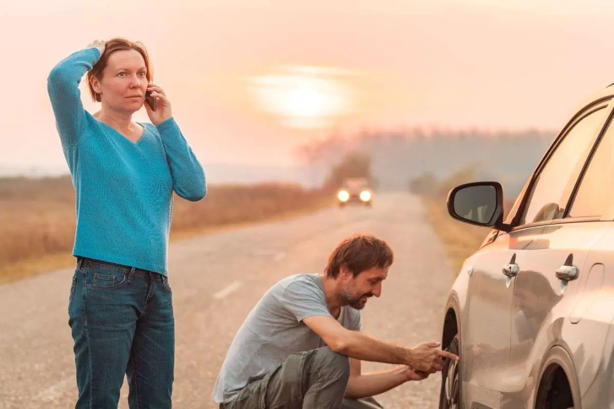 couples repairing tire on road